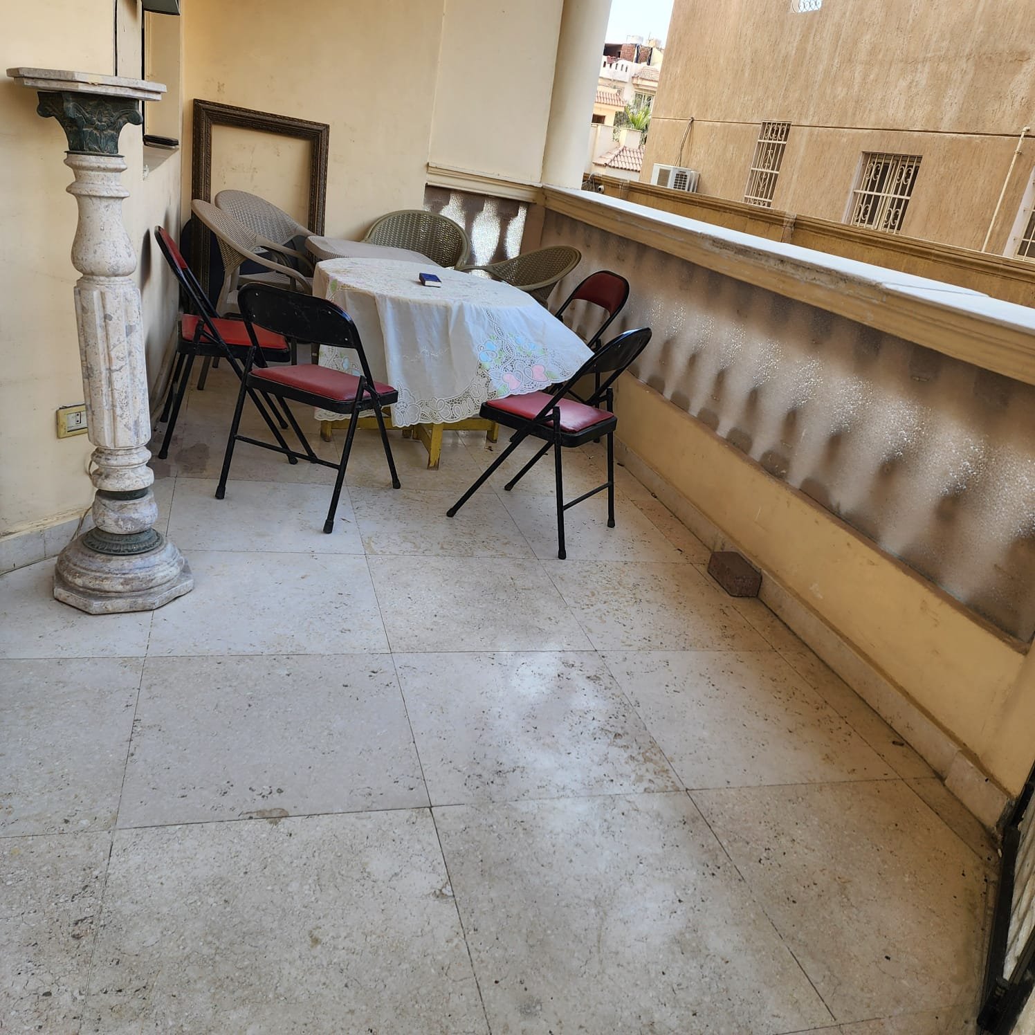 Covered balcony with a small table and folding chairs - apartment in Al Narges, New Cairo
