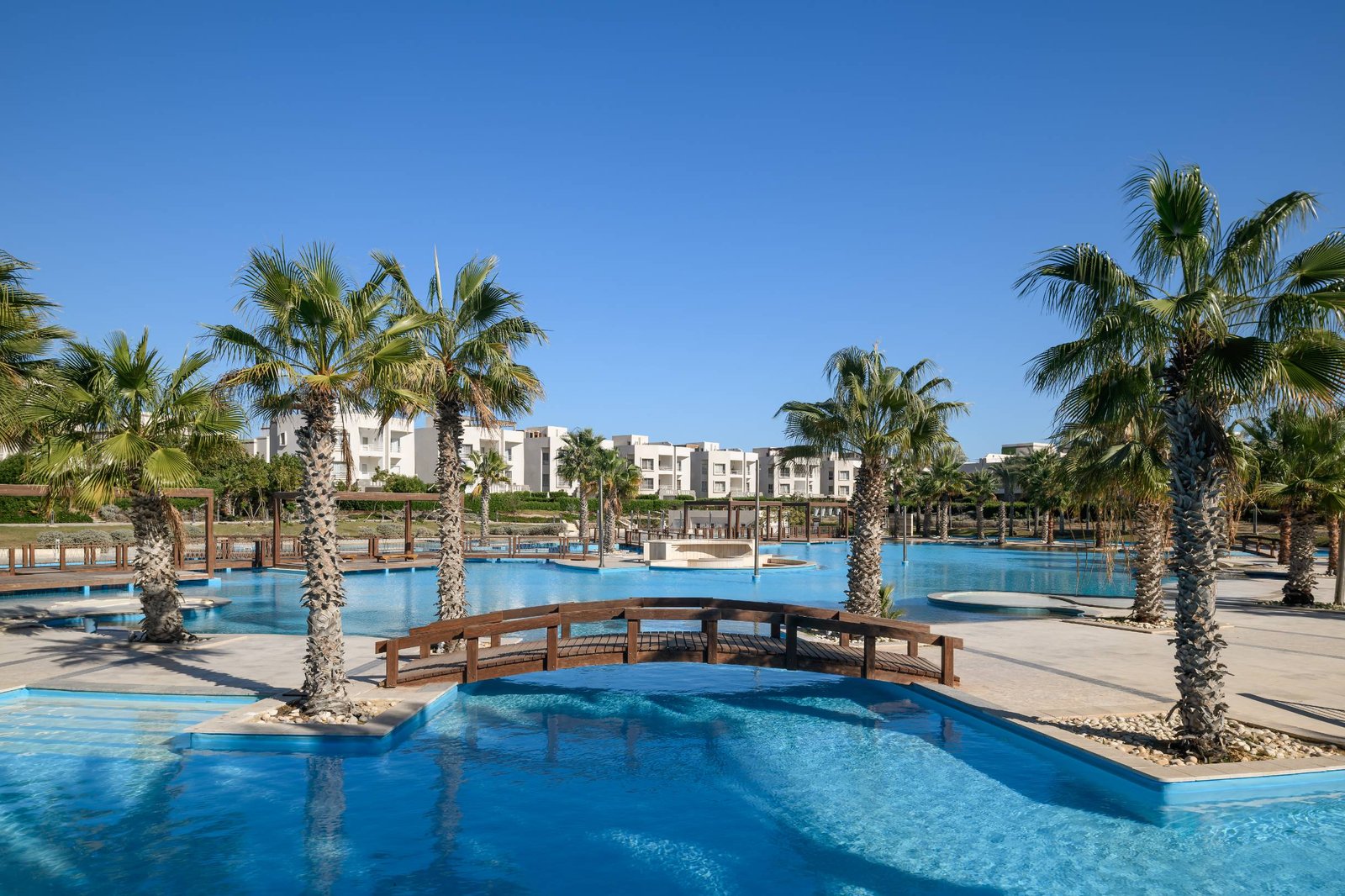 Footbridge over a lagoon pool among palm trees - chalet in Amwaj, North Coast