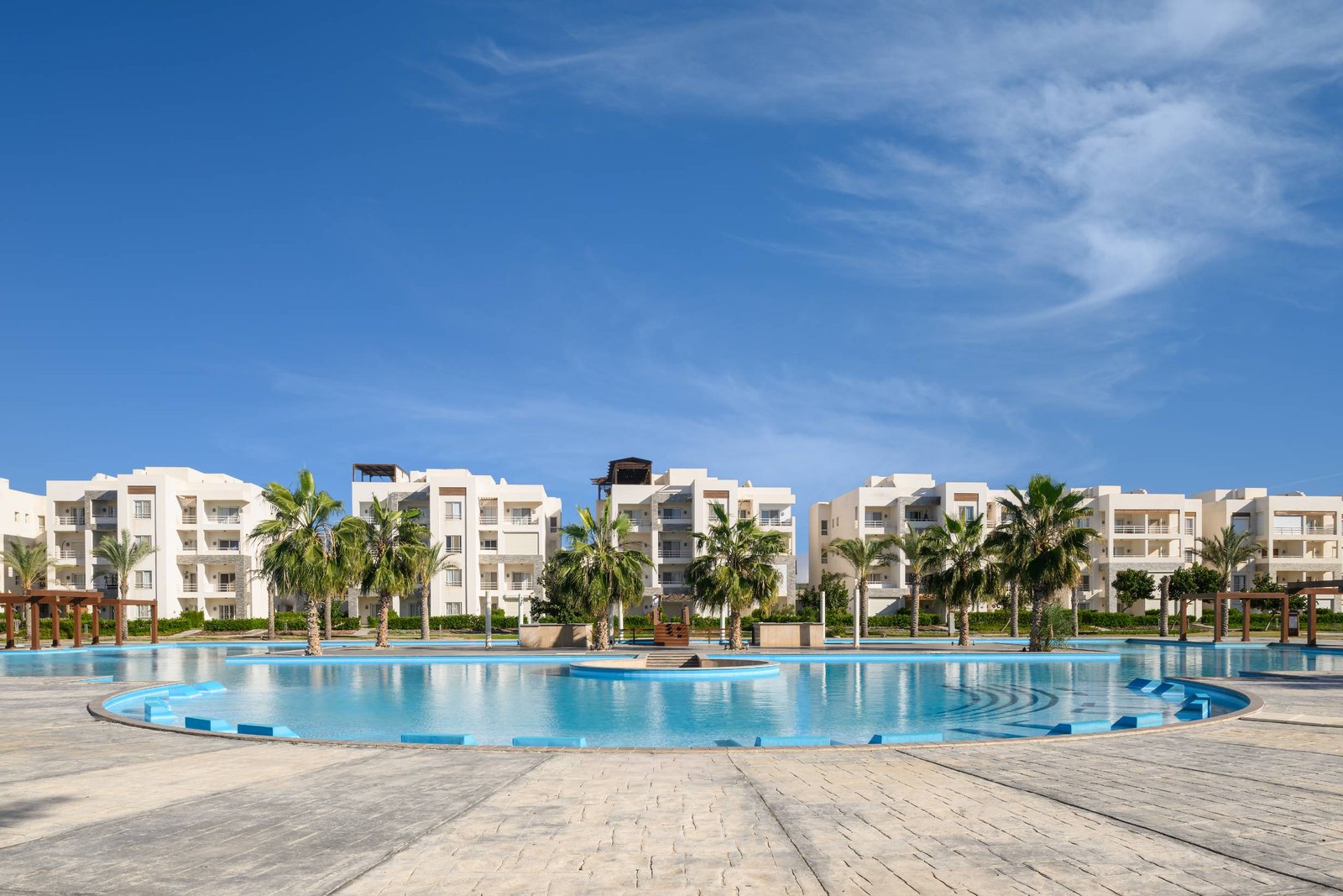 Round pool in front of white apartment buildings - chalet in Amwaj, North Coast