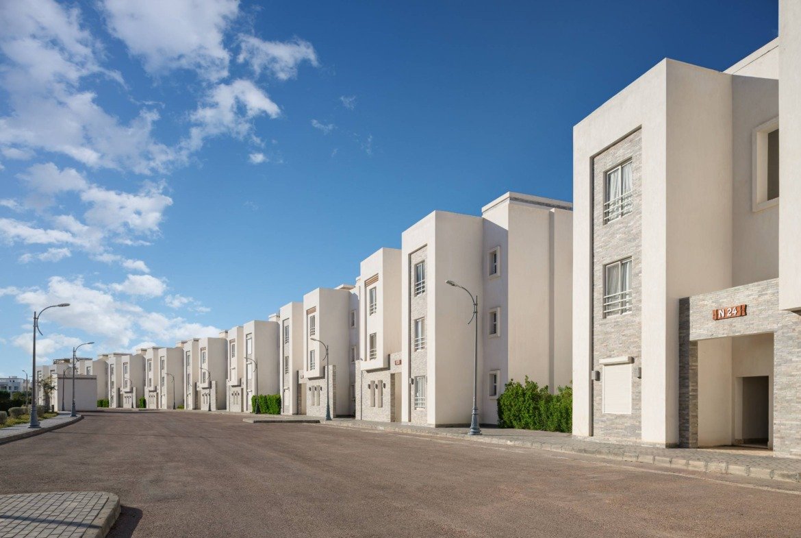 Street of white townhouses under a blue sky - chalet in Amwaj, North Coast