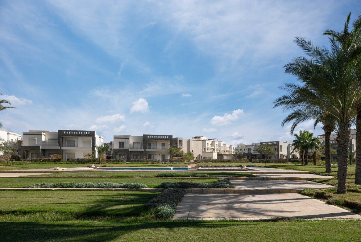 Lawn and walkway with villas and palm trees beyond - chalet in Amwaj, North Coast