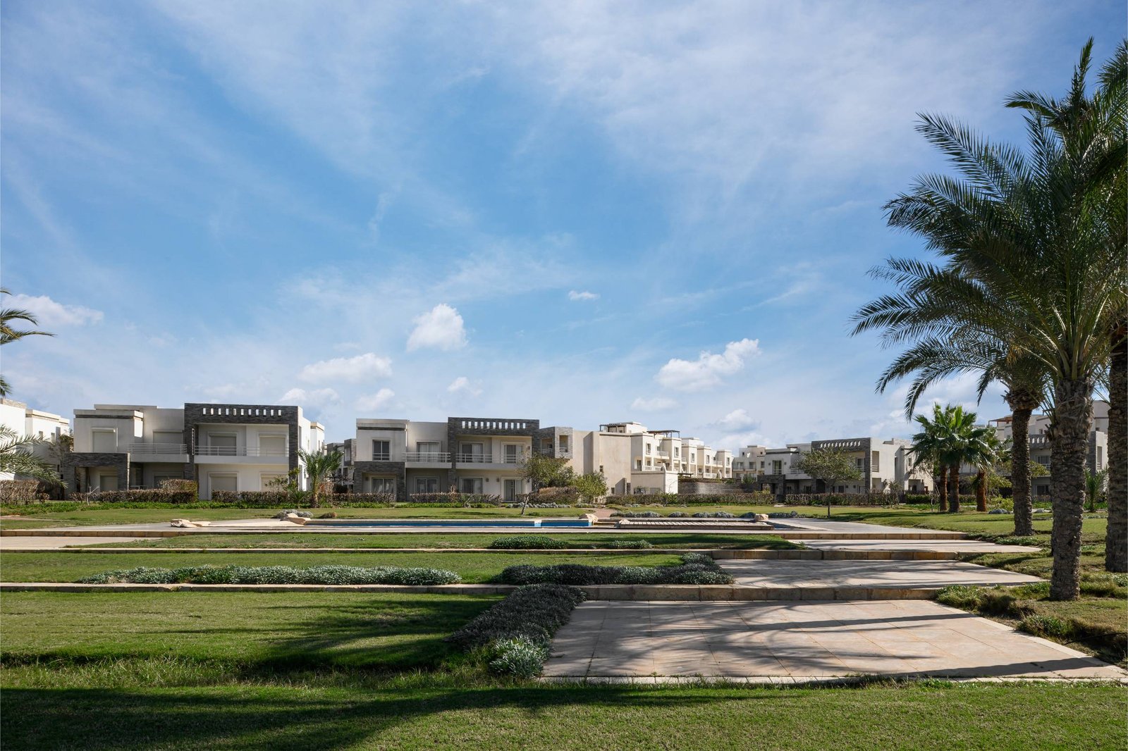 Lawn and walkway with villas and palm trees beyond - chalet in Amwaj, North Coast