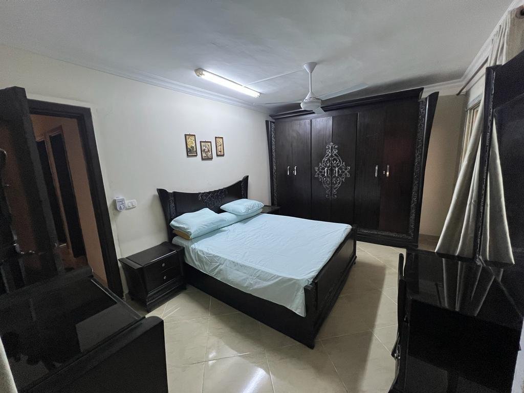 Bedroom with a dark wardrobe and a double bed - apartment in Dar Misr Al Andalus, 5th Settlement