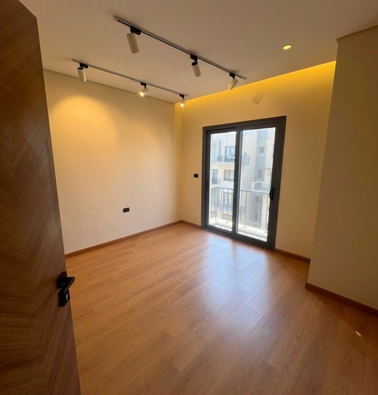 Room with a wood floor, track lights and a balcony door - apartment in SODIC Eastown, New Cairo