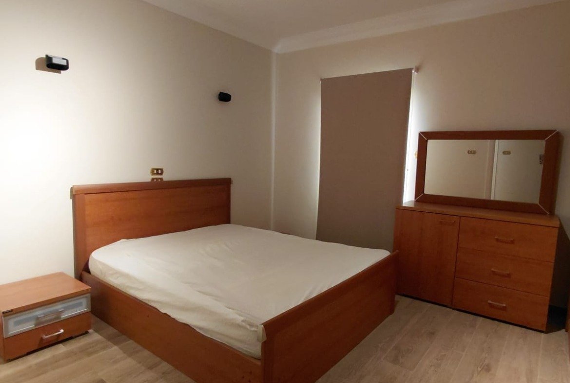 Bedroom with a wooden bed and a track light - villa in El Yasmeen 1 Villas, New Cairo