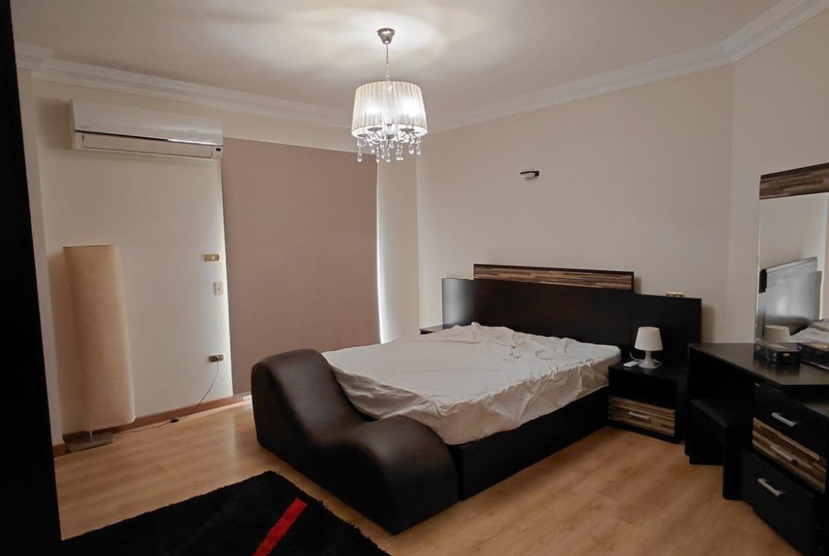 Bedroom with a red-and-black rug and a dark bed - villa in El Yasmeen 1 Villas, New Cairo