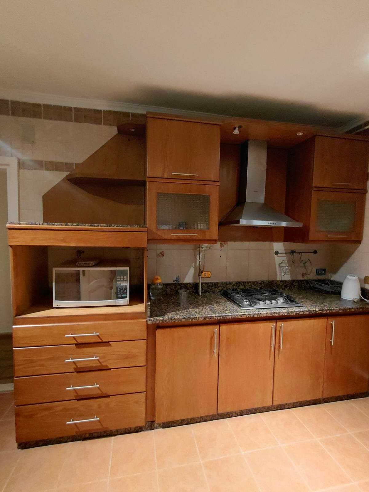Kitchen with wooden cabinets, a hood and a drawer unit - villa in El Yasmeen 1 Villas, New Cairo