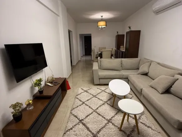 Furnished living room with corner sofa and TV, apartment for rent in Fifth Square New Cairo - غرفة معيشة مفروشة بركنة وتلفزيون، شقة للإيجار في فيفث سكوير القاهرة الجديدة