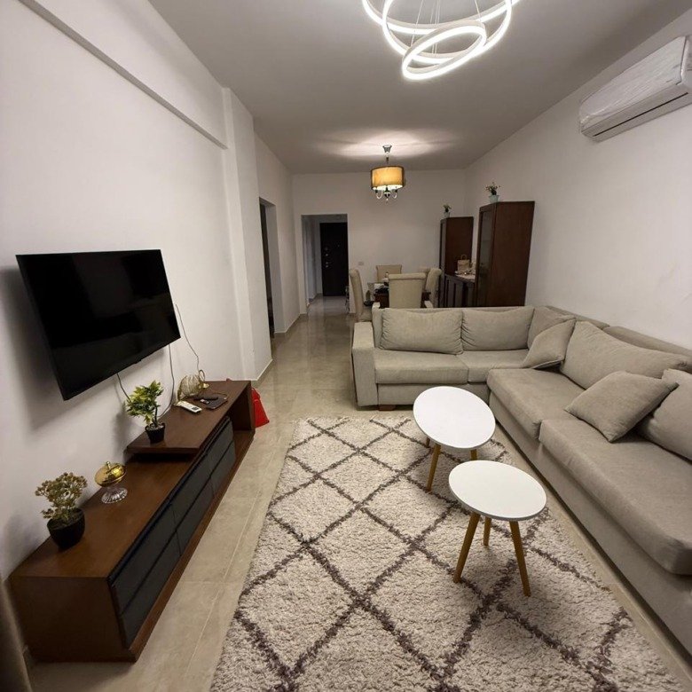 Furnished living room with corner sofa and TV, apartment for rent in Fifth Square New Cairo - غرفة معيشة مفروشة بركنة وتلفزيون، شقة للإيجار في فيفث سكوير القاهرة الجديدة