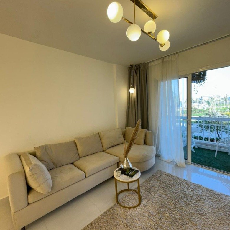 Living room with a beige sofa and a balcony door - apartment in Madinaty, New Cairo