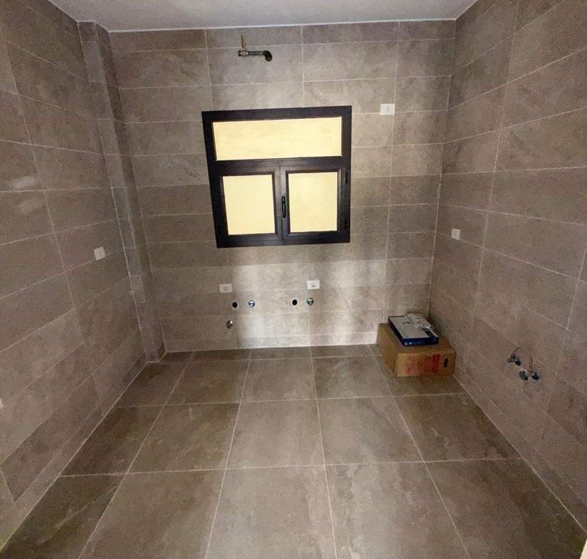 حمام خال ببلاط رمادي ونافذة - شقة في فيفث سكوير، القاهرة الجديدة