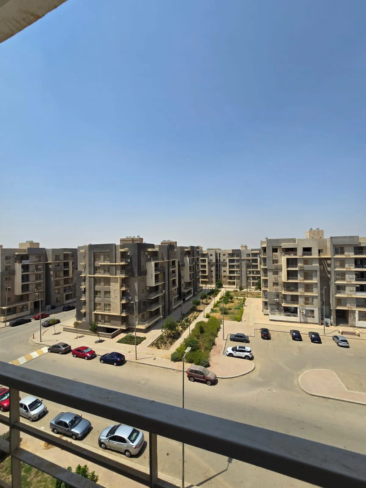 apartment-for-sale-dar-misr-al-andalus-new-cairo-130-sqm-compound-view منظر بلكونة على عمارات سكنية وموقف سيارات - شقة في دار مصر الأندلس، القاهرة الجديدة