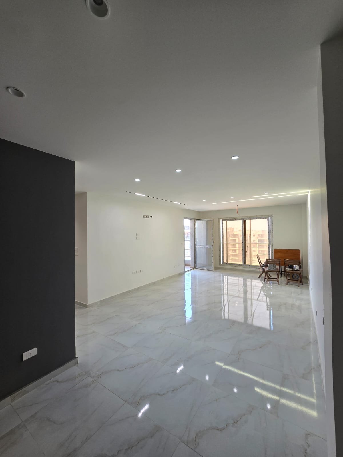 apartment-for-sale-dar-misr-al-andalus-new-cairo-130-sqm-reception صالة كبيرة فاضية برخام رمادي لامع وحائط داكن - شقة في دار مصر الأندلس، القاهرة الجديدة