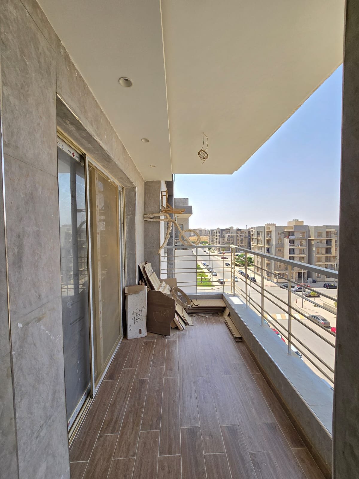 apartment-for-sale-dar-misr-al-andalus-new-cairo-130-sqm-terrace بلكونة بأرضية شبه الخشب وإطلالة على العمارات المجاورة - شقة في دار مصر الأندلس، القاهرة الجديدة