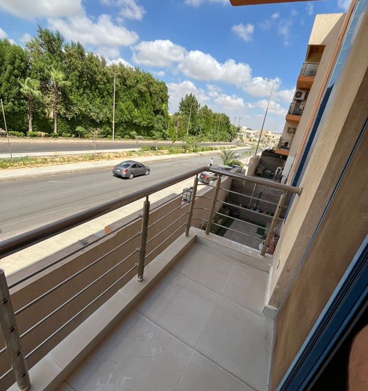 Balcony with a trimmed railing and a green view - apartment in Eazy Life, New Cairo