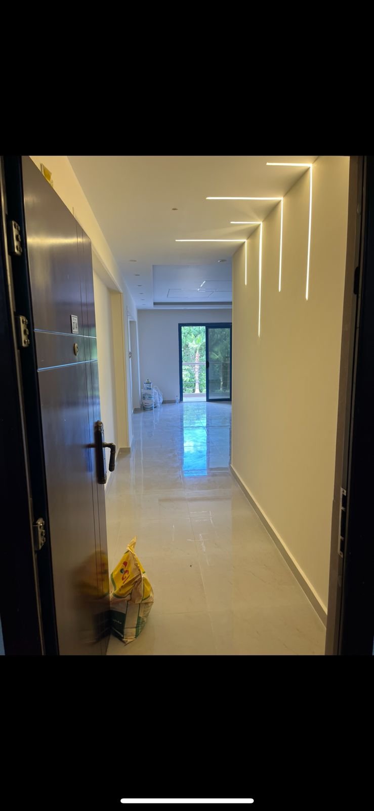 Hallway with a lit ceiling and a view of the hall beyond - apartment in Eazy Life, New Cairo