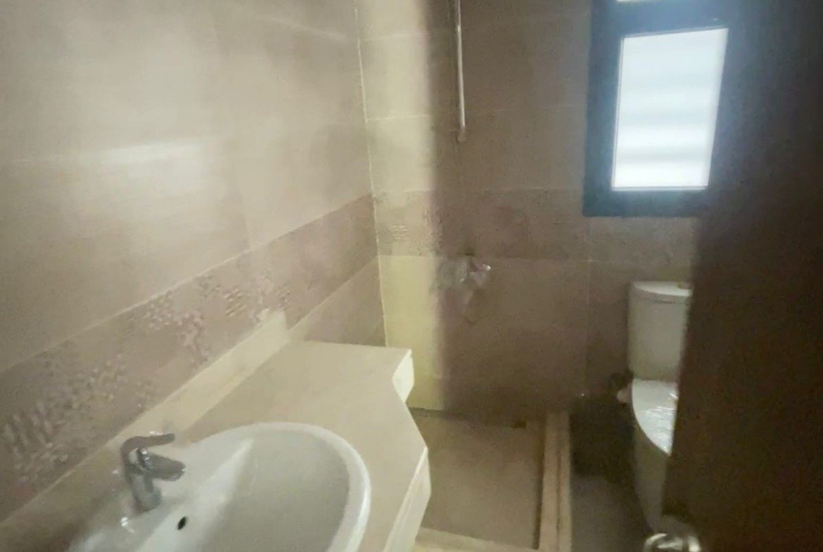 Bathroom with a white basin and a small shower window - apartment in Privado, New Cairo