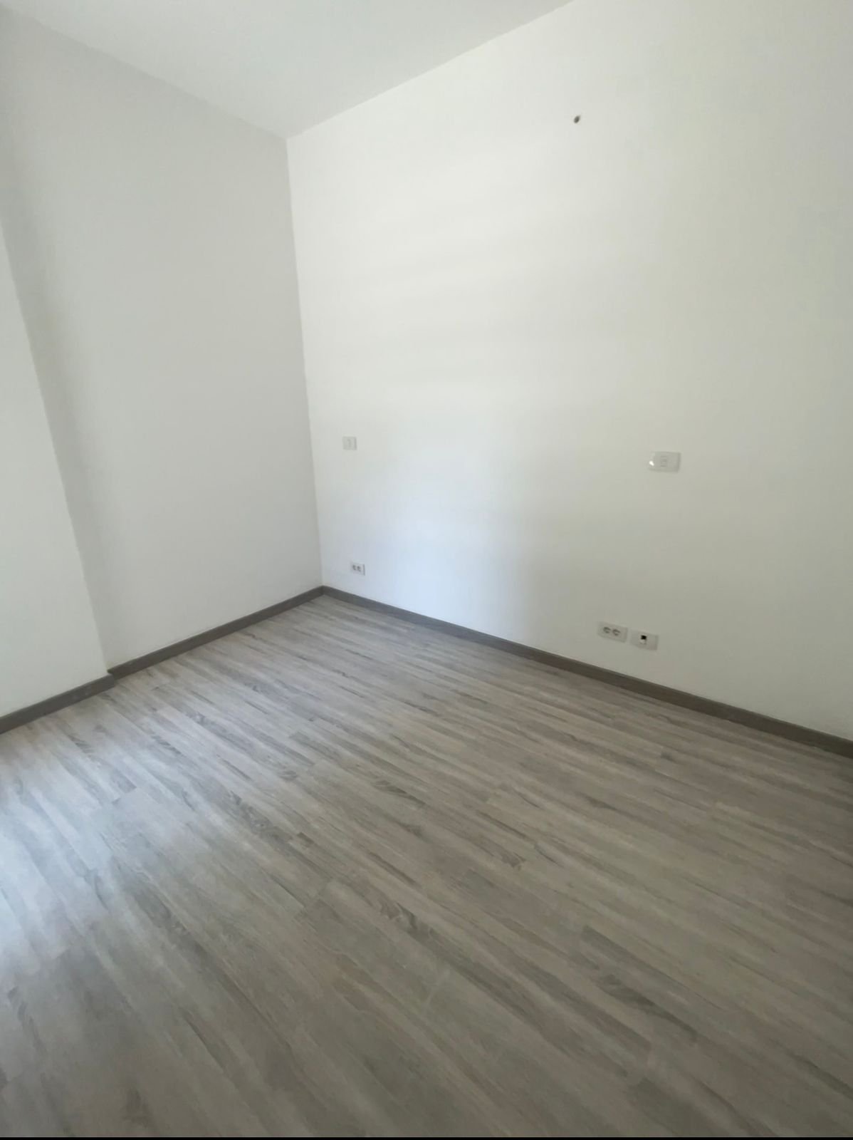 Empty room with white walls and a grey laminate floor - apartment in Privado, New Cairo