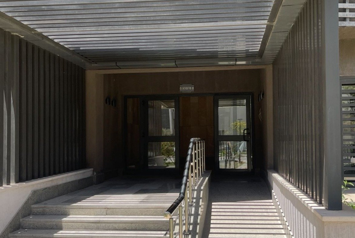 Building entrance with steps and a ramp under a canopy - apartment in Privado, New Cairo
