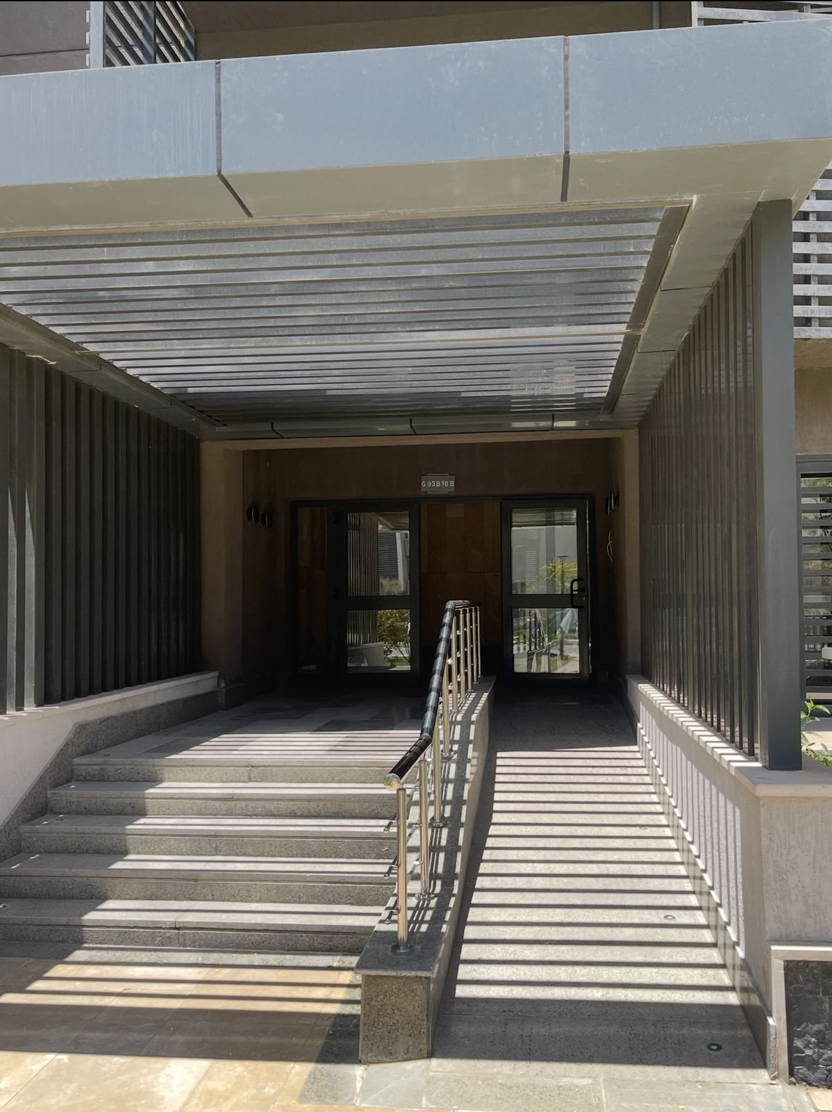 Building entrance with steps and a ramp under a canopy - apartment in Privado, New Cairo