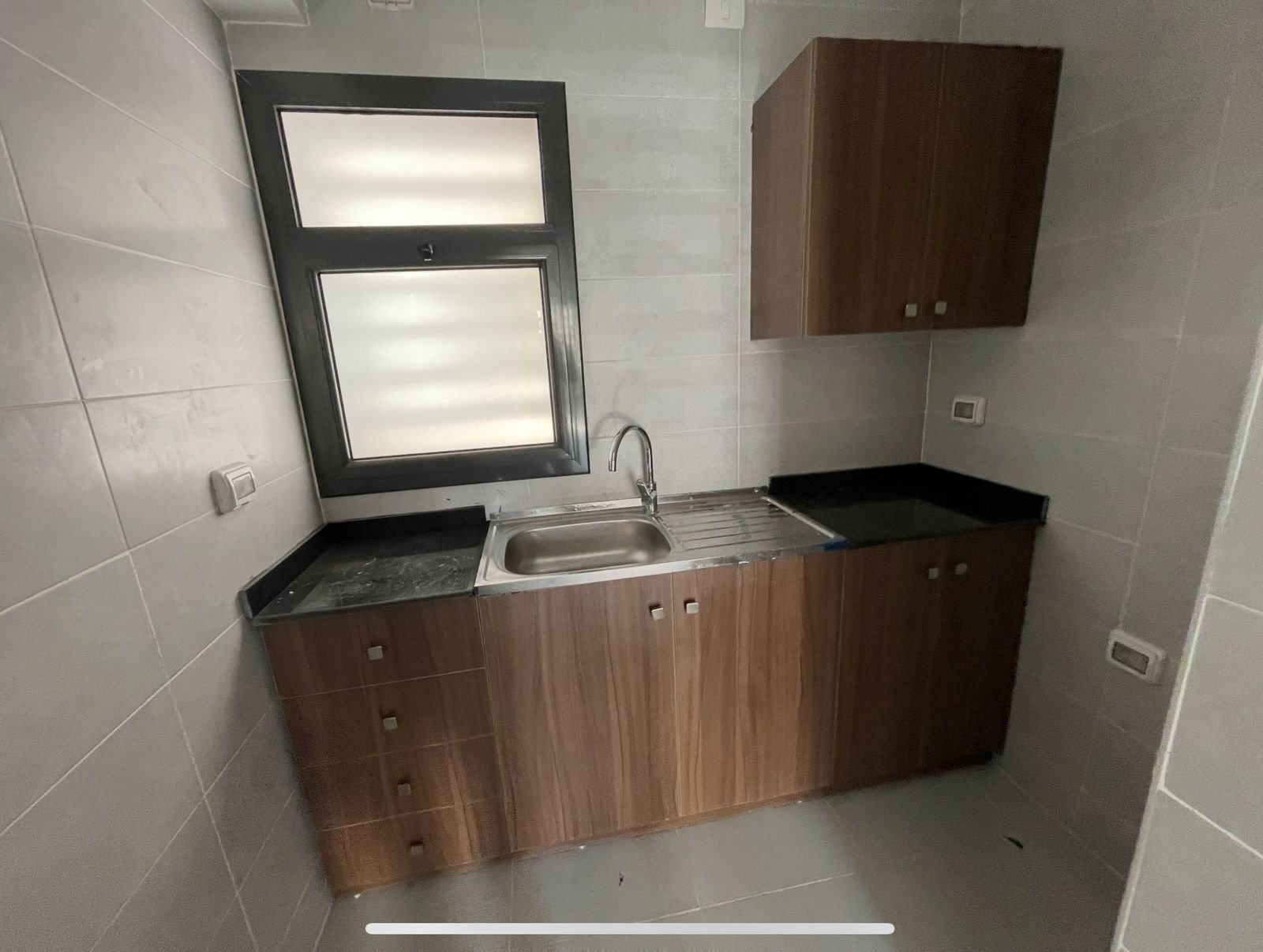 Small kitchen unit with a steel sink and wood cabinets - apartment in Privado, New Cairo