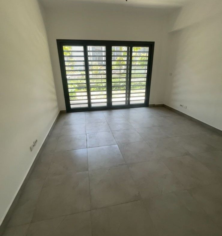 Room with a wide window and a grey floor - apartment in Privado, New Cairo