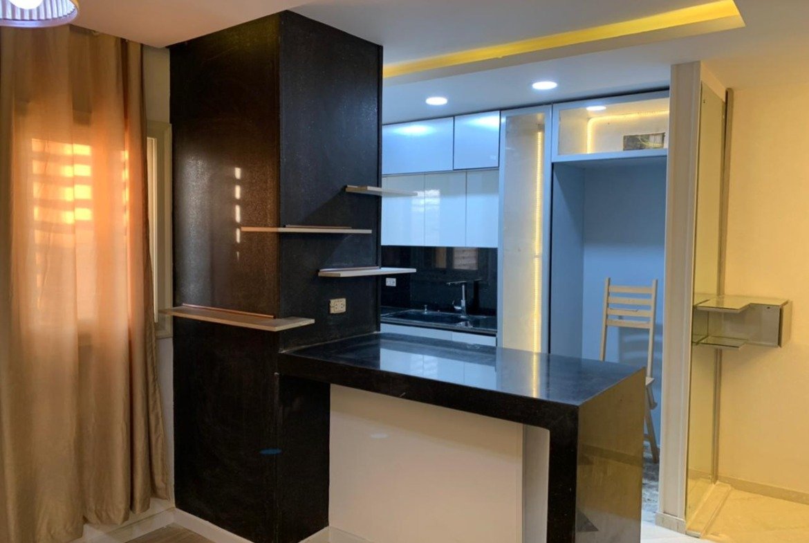 Open kitchen with a black breakfast bar and warm lighting - apartment in Sarai, Mostaqbal City