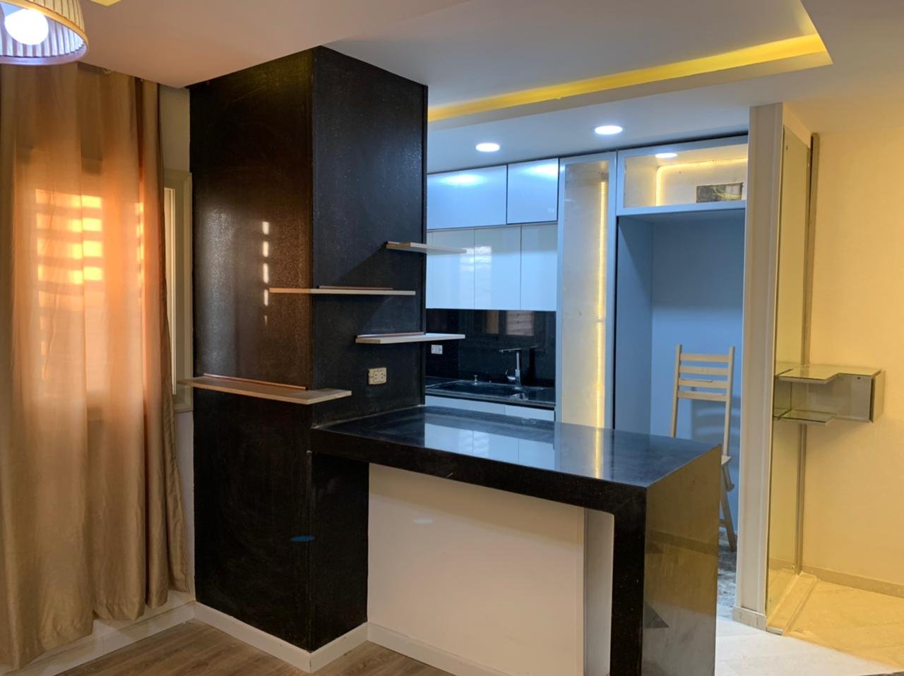 Open kitchen with a black breakfast bar and warm lighting - apartment in Sarai, Mostaqbal City