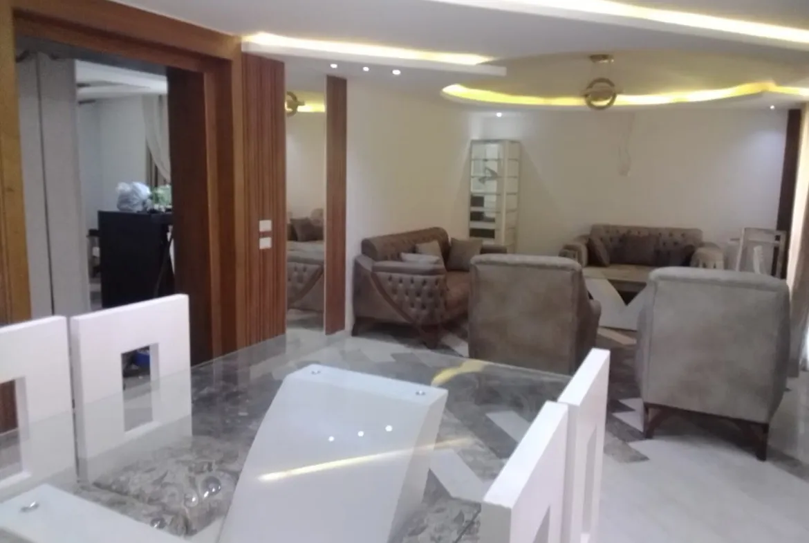 Marble dining table and white chairs in front of a sitting area - apartment in Sarai, Mostaqbal City