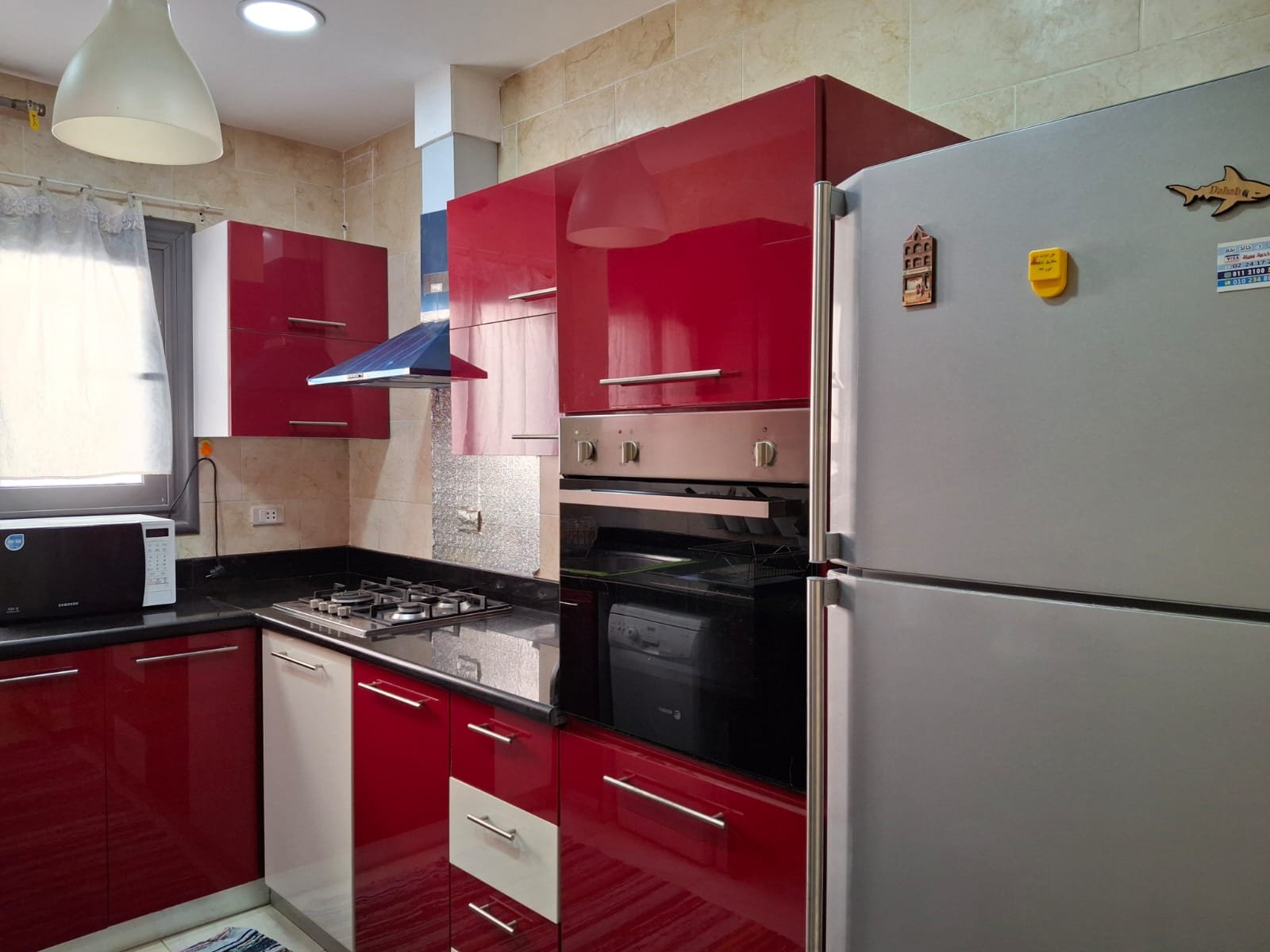 apartment-rent-tag-sultan-taj-city-34-kitchen-appliances مطبخ أحمر مع ثلاجة وفرن بلت إن - شقة في تاج سلطان