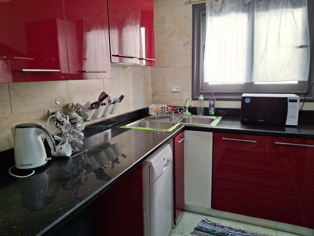 apartment-rent-tag-sultan-taj-city-34-kitchen مطبخ مع خزائن حمراء لامعة وكاونتر أسود - شقة في تاج سلطان