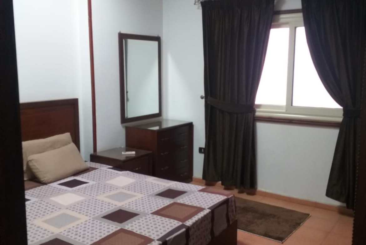 Bedroom with a checkered bed cover and dark curtains - apartment in Yasmeen 3, New Cairo