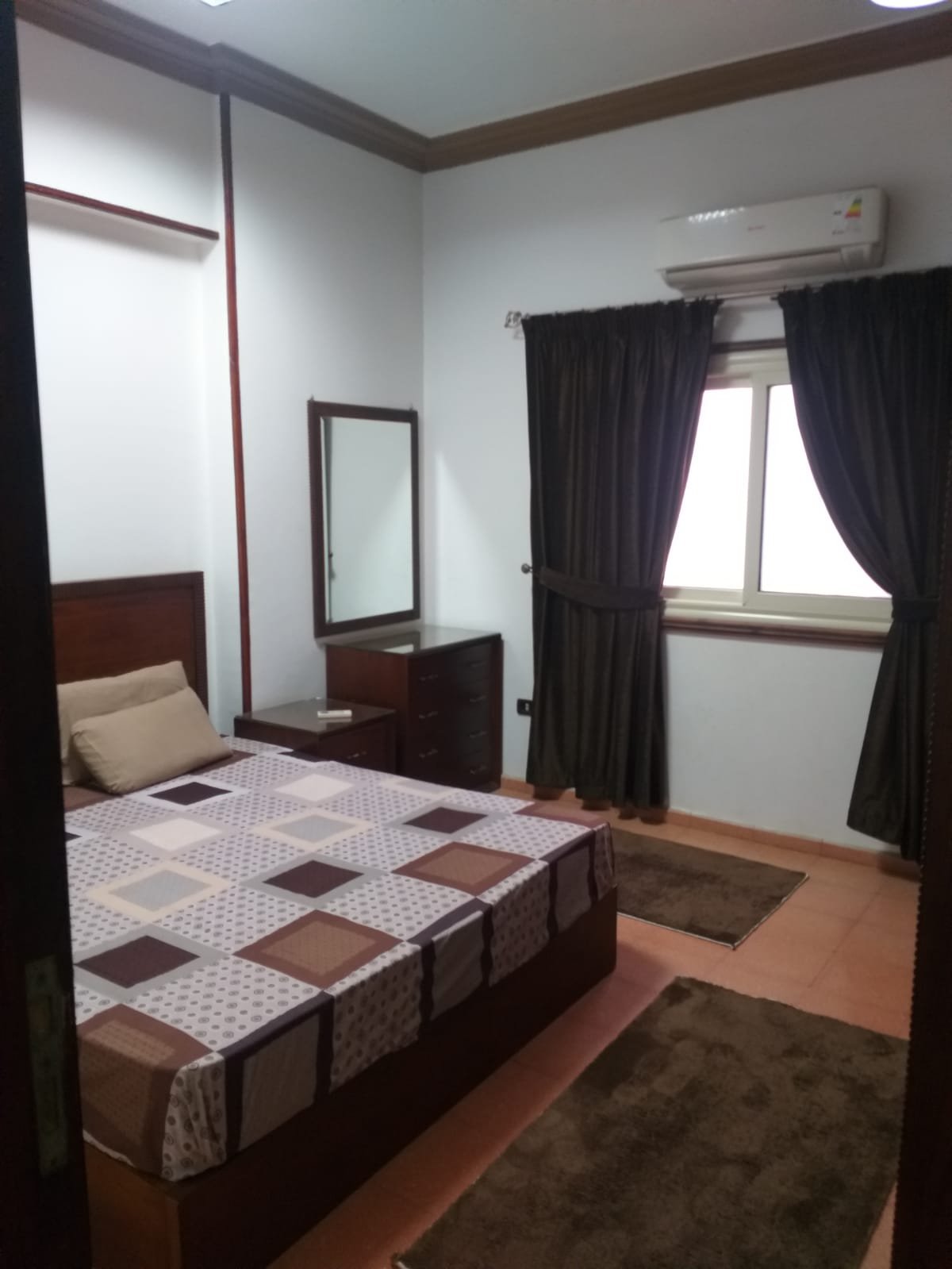 Bedroom with a checkered bed cover and dark curtains - apartment in Yasmeen 3, New Cairo
