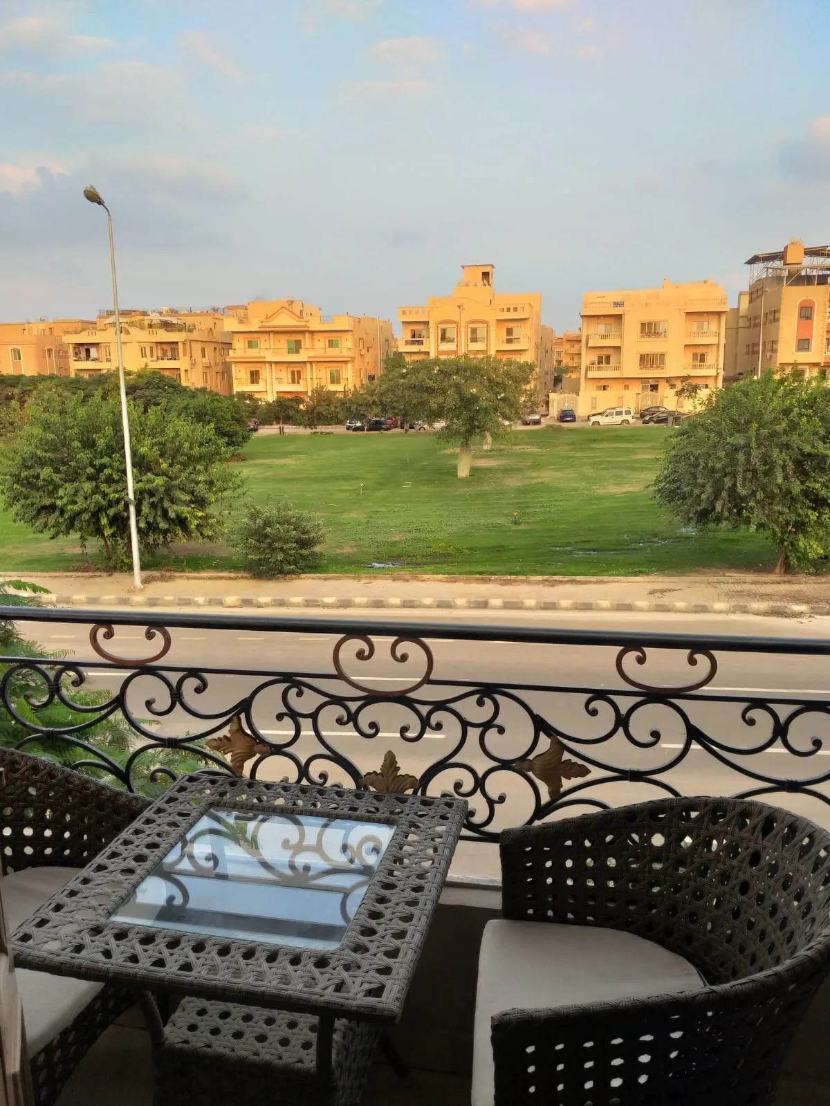 Balcony with a small table and chairs overlooking a green lawn - apartment in Yasmeen 3, New Cairo