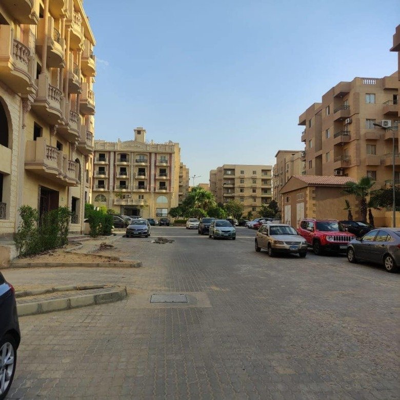 Quiet street between apartment buildings with parked cars - apartment in Ashrafeya Residence, New Cairo