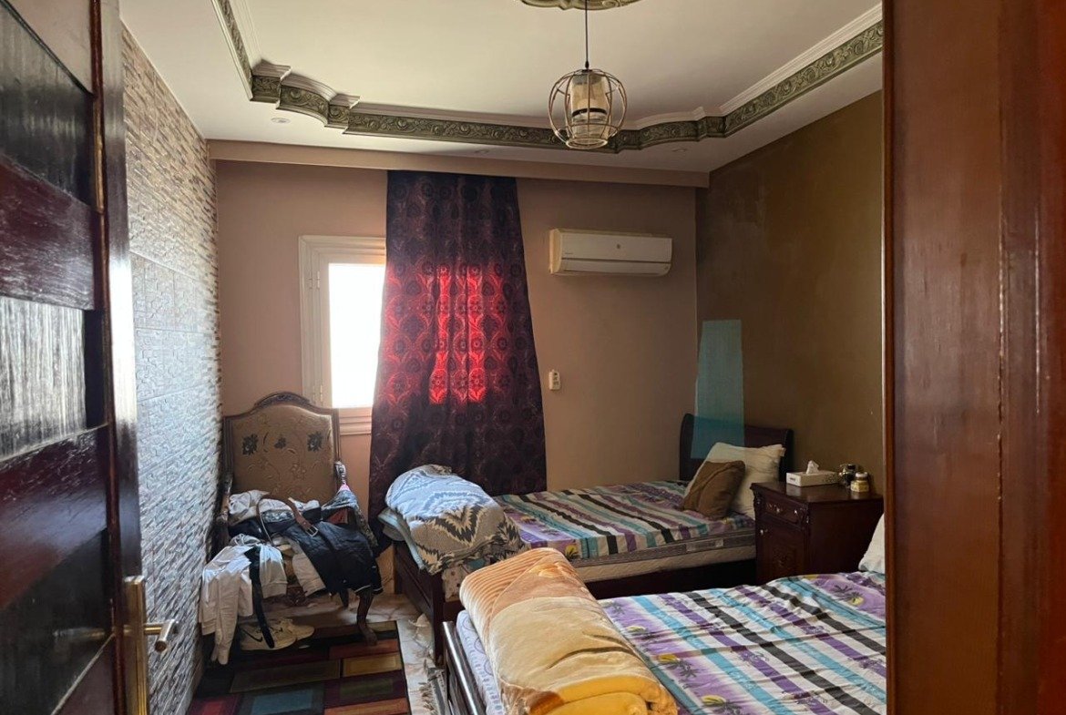 Bedroom with striped bedspread and wine-red curtains - apartment in Banafseg Buildings, New Cairo