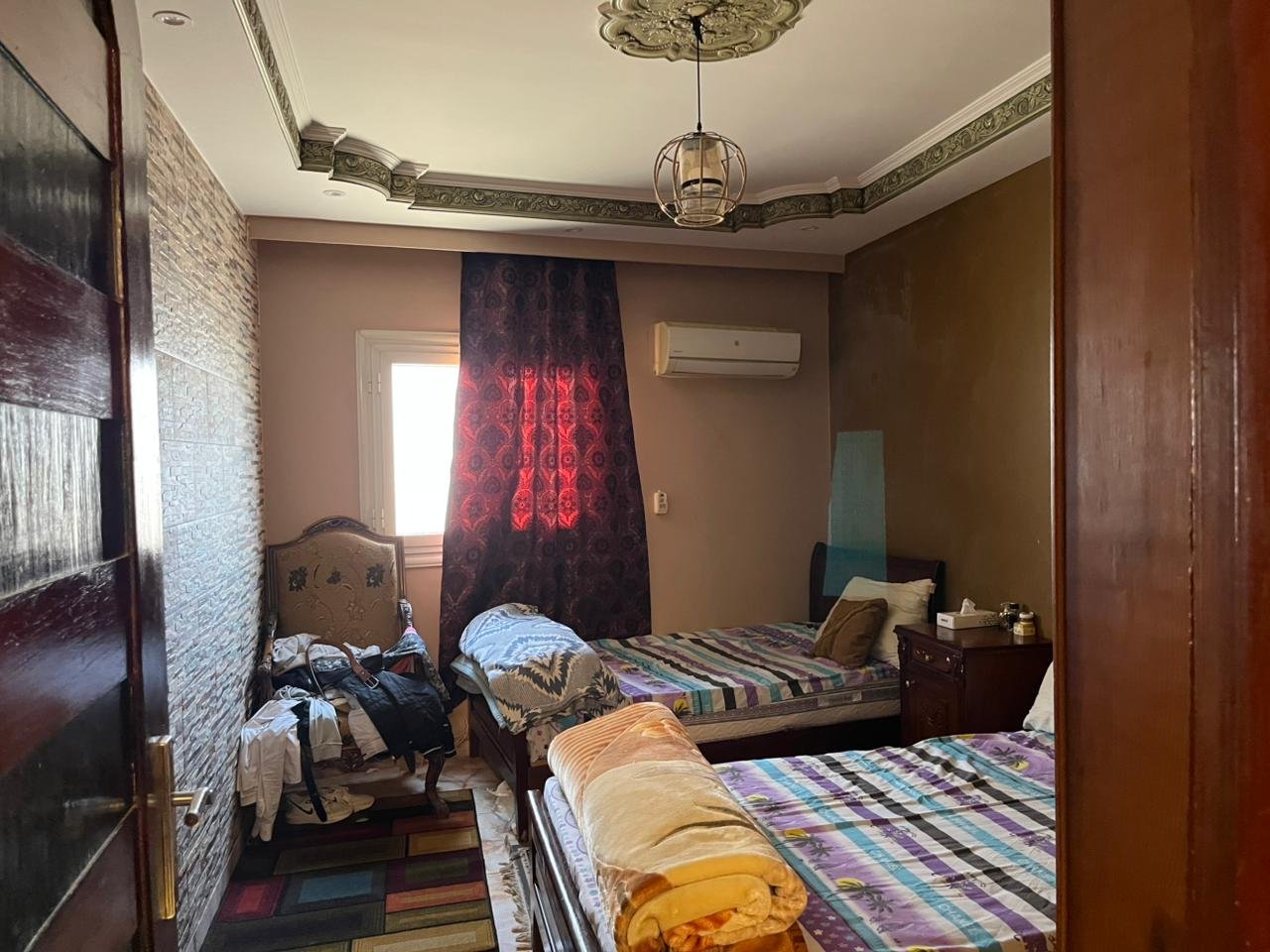 Bedroom with striped bedspread and wine-red curtains - apartment in Banafseg Buildings, New Cairo