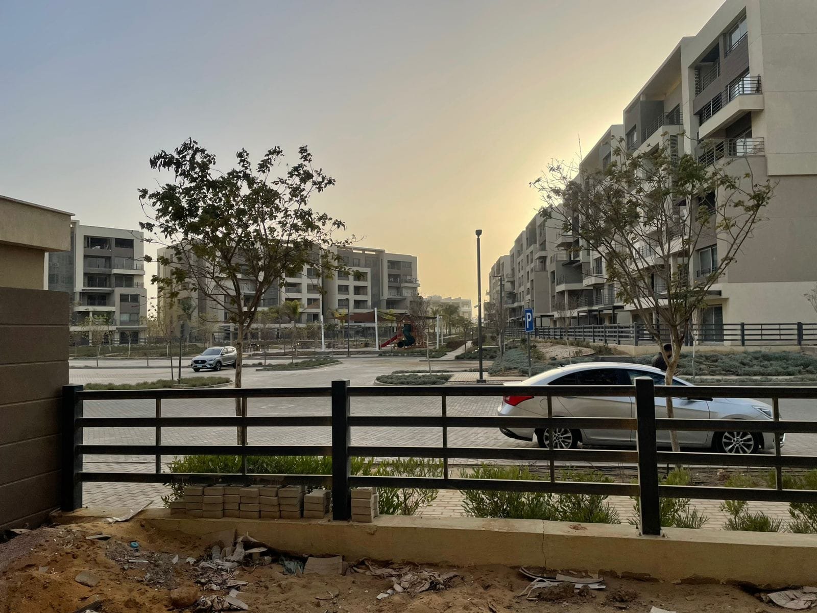 capital-gardens-mostakbal-city-compound-10 منظر من الشارع لبلوكات سكنية خلف سور أسود وقت الغروب - شقة في كابيتال جاردنز بجوار مدينتي، مدينة المستقبل