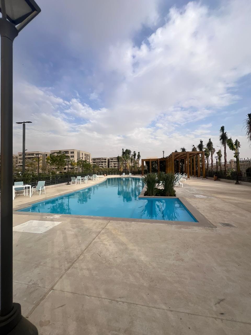 capital-gardens-mostakbal-city-compound-8 منطقة حمام سباحة بحمام أزرق وبرجولة خشب ونخيل - شقة في كابيتال جاردنز بجوار مدينتي، مدينة المستقبل