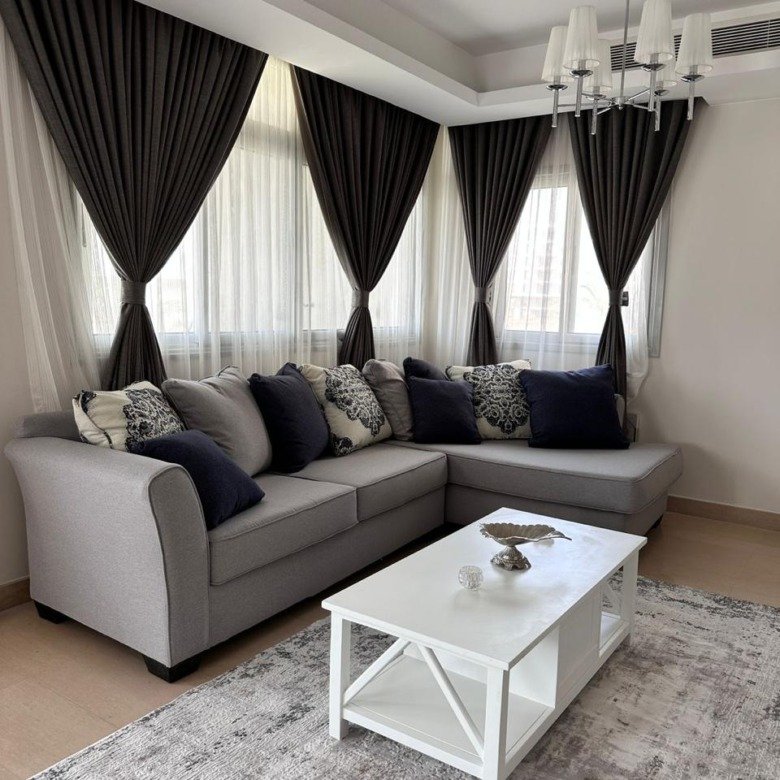 Grey corner sofa with a white coffee table and black curtains - apartment in Cairo Festival City New Cairo – 3 Bedrooms 200 sqm, New Cairo
