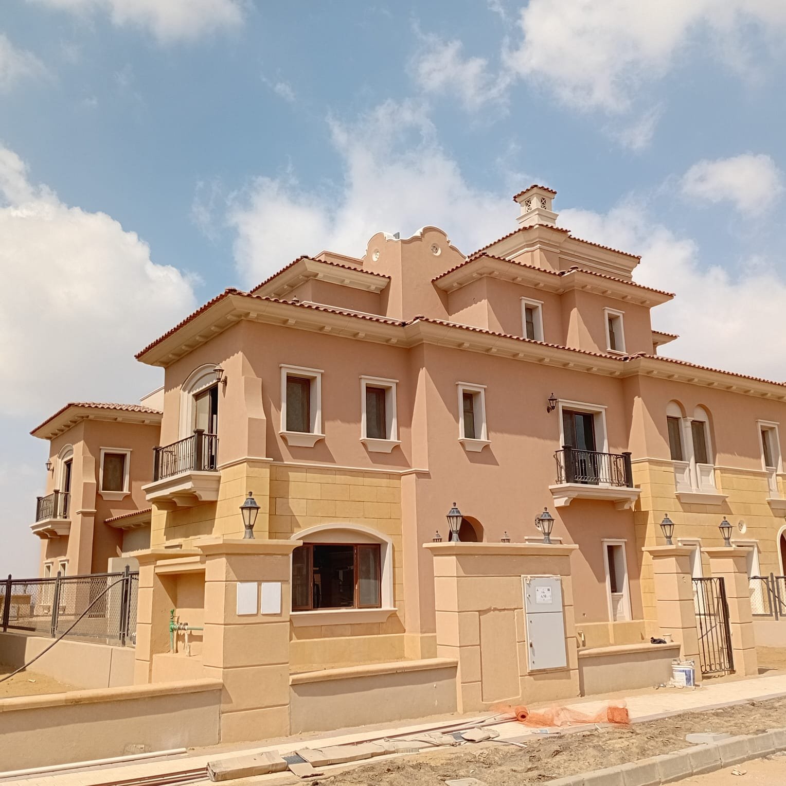 صف فيلات في سيتي جيت Row of villas with terracotta walls under a bright sky - villa in CityGate, New Cairo