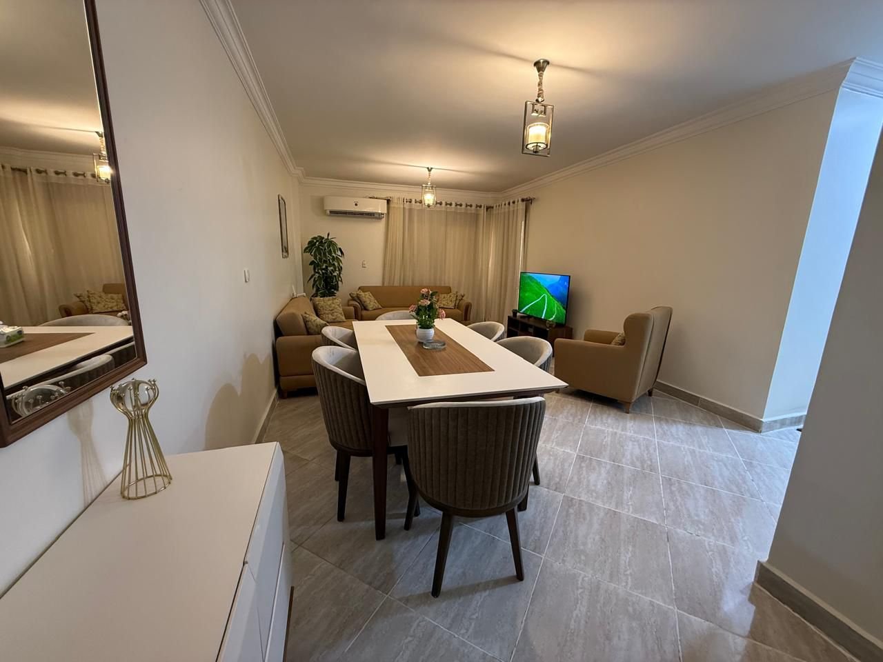 dar-misr-koronfol-apt-rent-097-02 Dining table with grey chairs beside the living area - apartment in Dar Misr Al Koronfol New Cairo – 3 Bedrooms 130 sqm, New Cairo