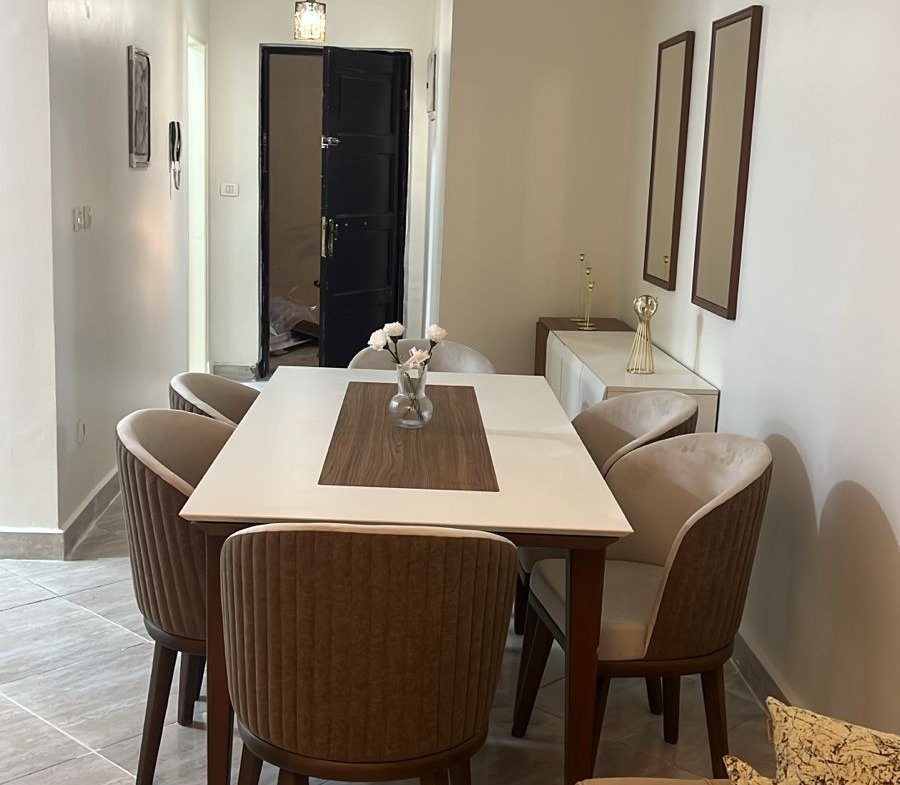 Dining set with brown chairs in a bright hallway - apartment in Dar Misr Al Koronfol New Cairo – 3 Bedrooms 130 sqm, New Cairo