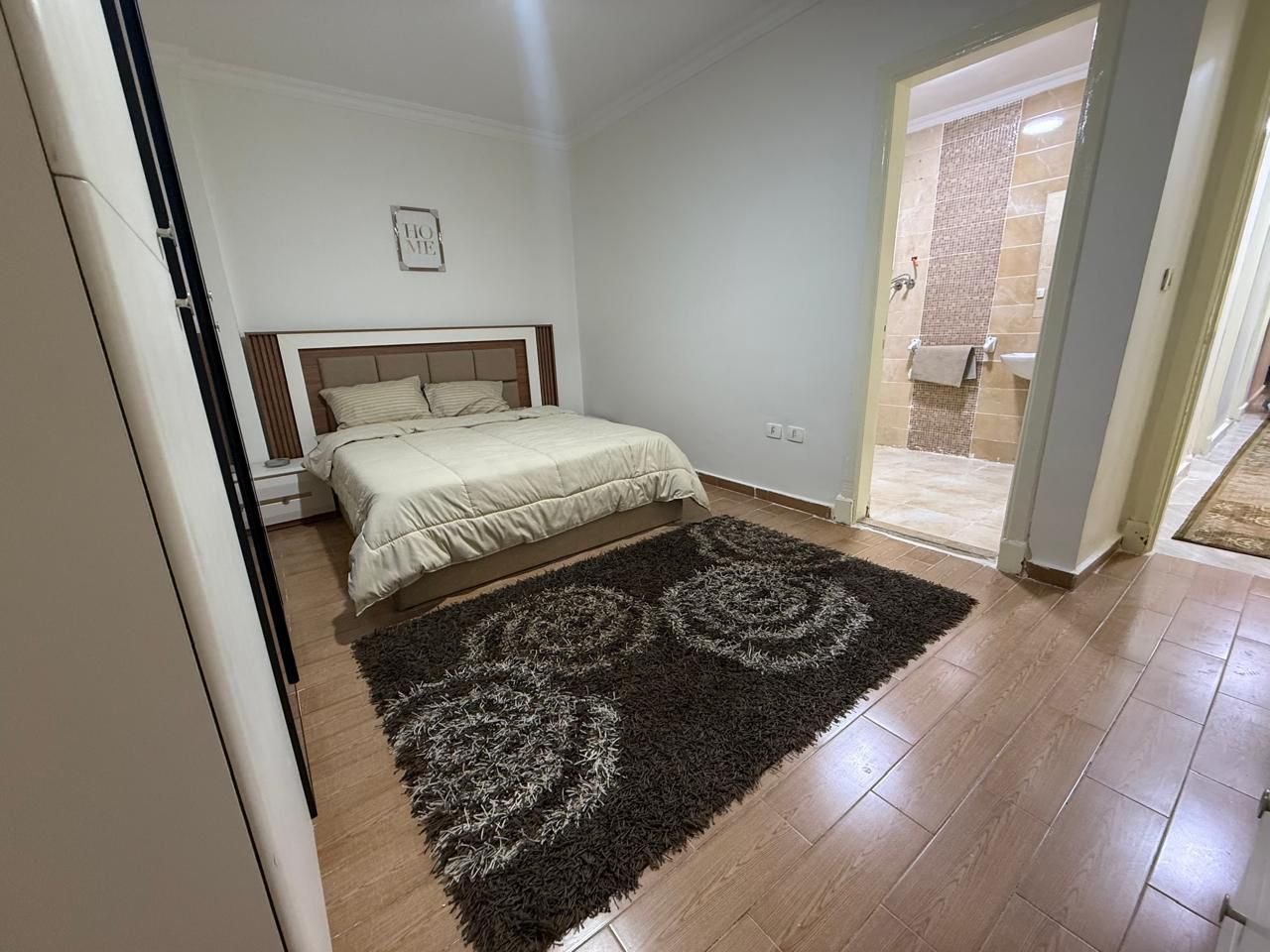 dar-misr-koronfol-apt-rent-097-06 Bedroom with a dark shaggy rug and an en-suite door - apartment in Dar Misr Al Koronfol New Cairo – 3 Bedrooms 130 sqm, New Cairo