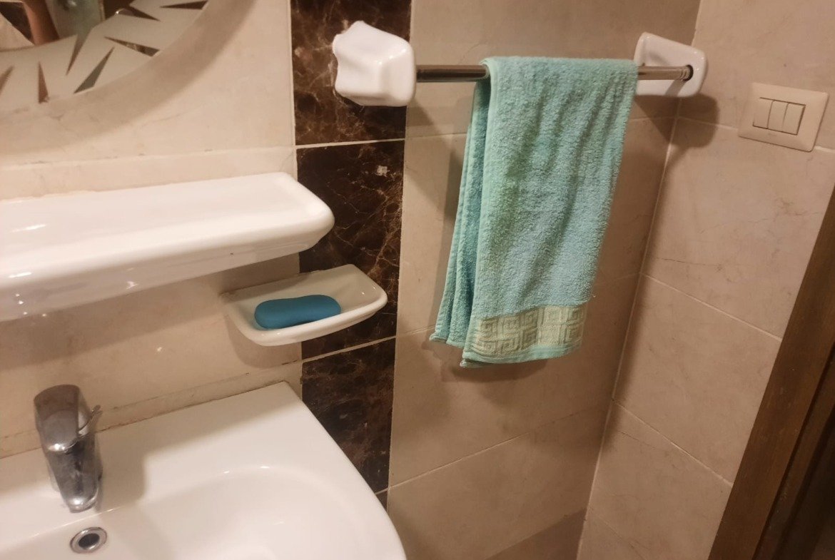 Washbasin with a soap dish and a green towel - duplex in Porto, New Cairo