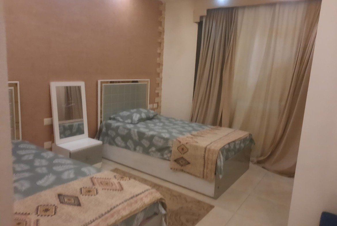 Bedroom with a floral bed set and a white mirror frame - duplex in Porto, New Cairo