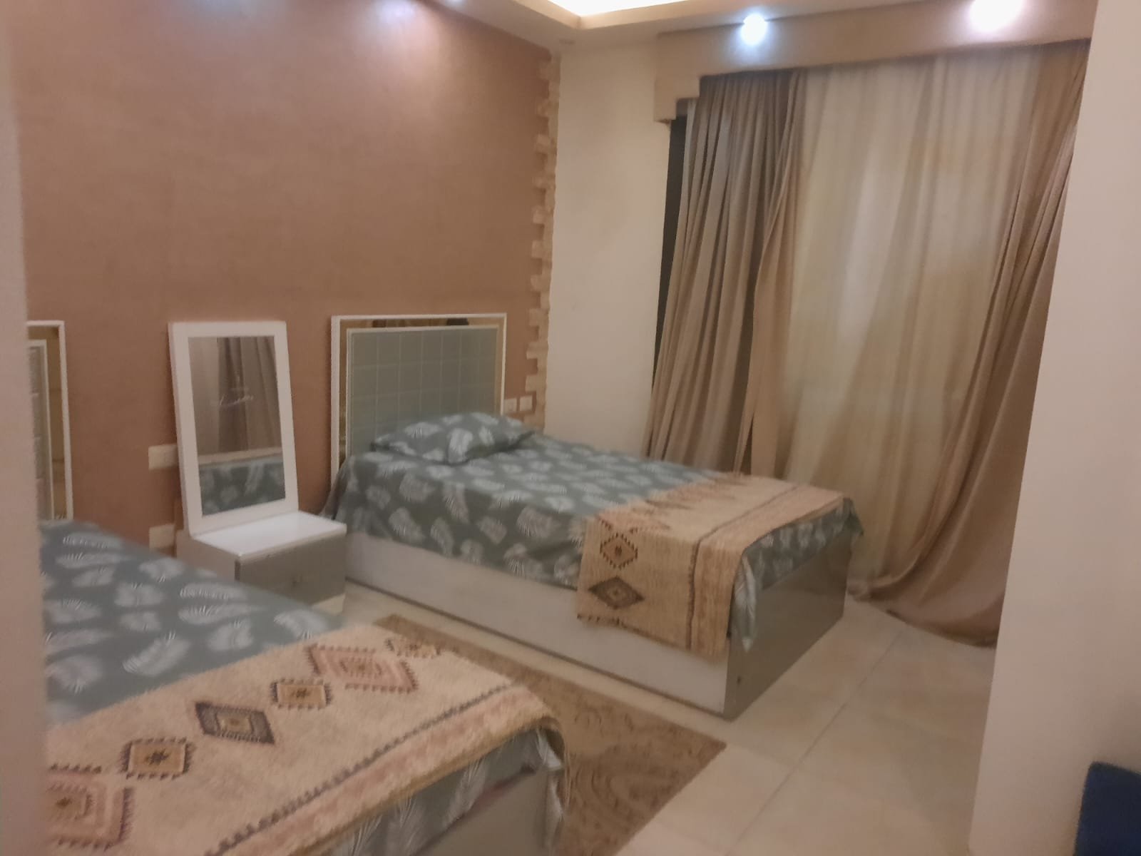 Bedroom with a floral bed set and a white mirror frame - duplex in Porto, New Cairo