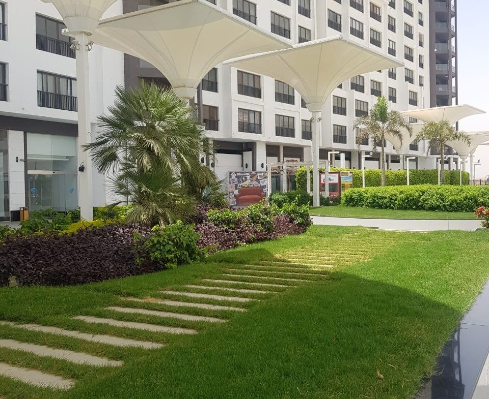 Green lawn with stepping stones in front of a white building - duplex in Porto, New Cairo