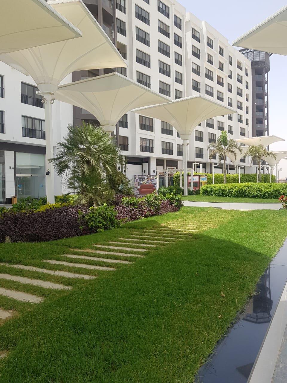 Green lawn with stepping stones in front of a white building - duplex in Porto, New Cairo