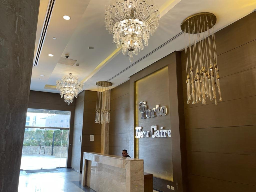 Hotel-style lobby with a reception desk and crystal chandeliers - duplex in Porto, New Cairo